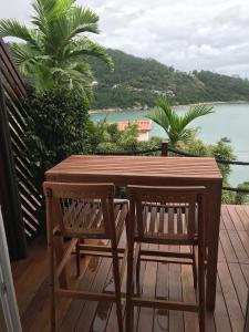 a wooden table and two chairs on a deck with the water at Mar de Bougainville in Governador Celso Ramos