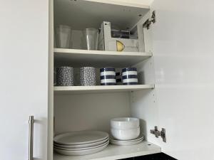 a pantry with plates and bowls on shelves at Stylish and Spacious in Kettering