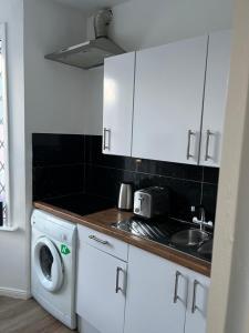 eine Küche mit einer Spüle und einer Waschmaschine in der Unterkunft Stylish and Spacious Wi-Fi Smart TV Tea and coffee in Kettering