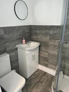 a bathroom with a sink and a toilet and a mirror at Stylish and Spacious in Kettering