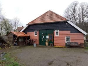 Vierakker的住宿－Nieuw ingerichte pipowagen bij Zutphen en IJssel!，一座带棚子的红色绿色大建筑