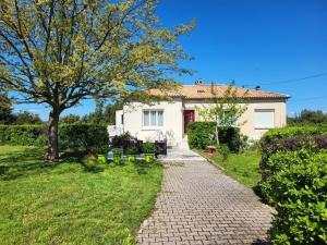 una casa blanca con un árbol y una pasarela de ladrillo en VILLA BOIS LAUZON, en Orange