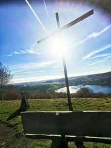 ein Kreuz auf einem Hügel mit der Sonne in der Unterkunft Ferienhaus Schwalbennest Schalkenmehren in Schalkenmehren