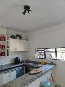 a kitchen with white cabinets and a ceiling at Casa de hóspedes Caraguatatuba in Caraguatatuba