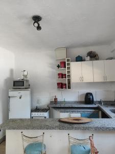 a kitchen with white cabinets and a white refrigerator at Casa de hóspedes Caraguatatuba in Caraguatatuba