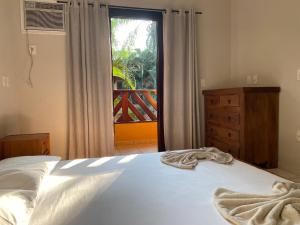 a bedroom with a bed and a view of a balcony at Maresias-200m.praia_CASA_2 suítes_cond. fec.ALOHA in São Sebastião