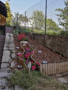 un jardin avec des fleurs roses et une clôture dans l'établissement Nadia Haus, à Luserna