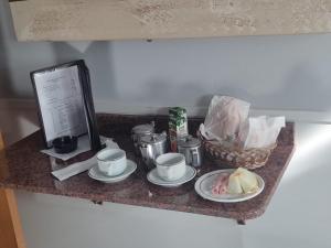 a table with plates and cups and a basket of food at Hotel Nova Lisboa - Adult Only- in Sao Paulo