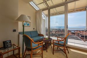 ein Wohnzimmer mit einem Sofa, Stühlen und einem Fenster in der Unterkunft Grand Hotel Bonavia in Rijeka