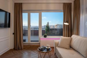 sala de estar con sofá y ventana grande en The Episode - Jacuzzi Penthouses en Cluj-Napoca