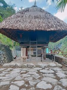 uma cabana com uma cadeira e um guarda-chuva de palha em Agamang Traditional House Inn em Banaue
