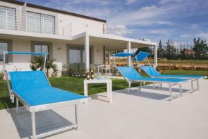 um pátio com cadeiras azuis e brancas em frente a uma casa em Ferienhaus in Partinico mit Privatem Pool em Balestrate
