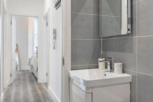 W łazience znajduje się biała umywalka i lustro. w obiekcie Rose Suite Camden Town 3 Bedroom Sleeps 11 w Londynie
