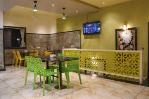 Hotel Garuda Executive Latur في Lātūr: غرفة طعام مع طاولة وكراسي وتلفزيون