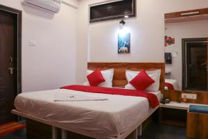 Hotel Garuda Executive Latur في Lātūr: غرفة نوم بسرير كبير ومخدات حمراء