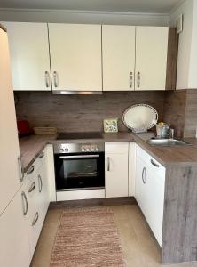 a kitchen with white cabinets and a sink at Ferienwohnung IDA in Peiting +17 photos