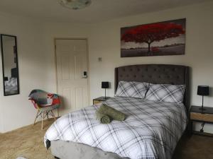a bedroom with a bed and a chair and a tree at MossBank House Luton Airport in Luton