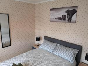 Schlafzimmer mit einem Bett und einem Bild von Elefanten in der Unterkunft MossBank House Luton Airport in Luton