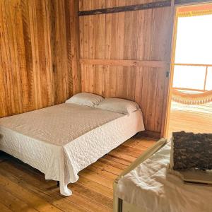 a small bed in a wooden room with a window at Hostel Capitão da Ilha in Maracanã