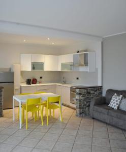 eine Küche mit einem Tisch, gelben Stühlen und einem Sofa in der Unterkunft L'Oasi Amena - Camera Salvia in Ameno