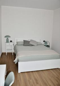 biała sypialnia z białym łóżkiem i stołem w obiekcie L'Oasi Amena - Camera Salvia w mieście Ameno