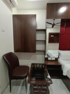 Zimmer mit einem Stuhl, einem Tisch und einem Bett in der Unterkunft Hotel Royal Grand - Near Mumbai International Airport in Mumbai