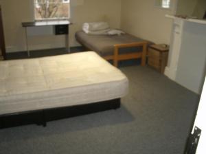 a bedroom with two beds and a table and a refrigerator at Contractors House Edgbaston in Birmingham