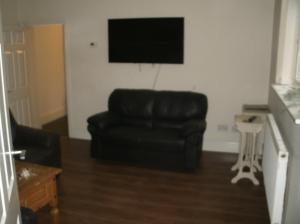a living room with a black couch and a flat screen tv at Contractors House Edgbaston in Birmingham