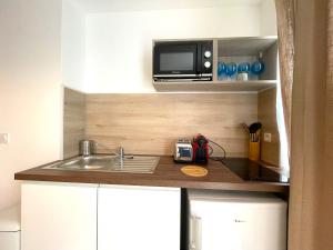 uma pequena cozinha com um lavatório e um micro-ondas em Les Entrepreneurs - Appartements neufs et spacieux, proche RER C et Aéroport Orly em Morangis