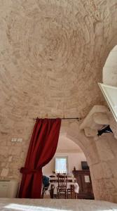 a room with a red curtain and a dining table at Trulli Beauty LAMIA in Martina Franca
