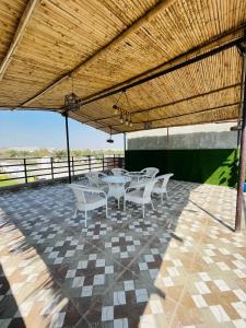 un patio con mesas blancas y sillas bajo un techo en Shimmer Farms, en Faridabad