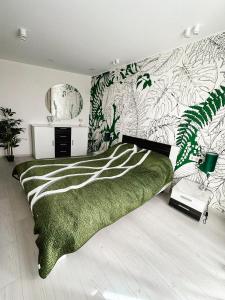 een slaapkamer met een groen bed en een muur met planten bij Jungle Apartments in Vinnytsya