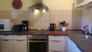 een keuken met een fornuis, een wastafel en een klok bij Apartment Gala, ruhige Lage, stadtnah in Bad Kissingen