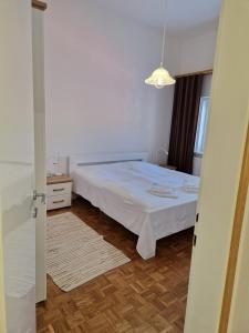 sypialnia z białym łóżkiem i drewnianą podłogą w obiekcie Dom Nazaret w mieście Nazarje
