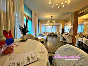 ミラノ・マリッティマにあるHotel Ambraの白いテーブルと椅子のあるレストラン、テーブルサブリックのある部屋