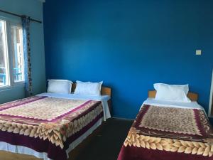 two beds in a room with a blue wall at Tranquil Water Guest House in Pokhara