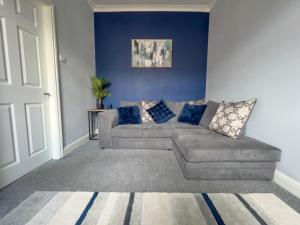 un soggiorno con divano e pareti blu di The Grey Bungalow a Waterhouses