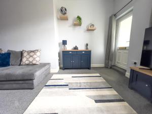 a living room with a couch and a tv at The Grey Bungalow in Waterhouses