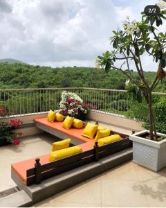 um banco com almofadas amarelas sentado numa varanda em The Woods Worth Villa em Vani