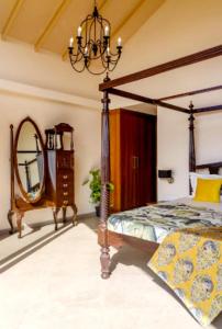 um quarto com uma cama de dossel e um espelho em The Woods Worth Villa em Vani