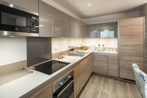 a kitchen with stainless steel appliances and wooden cabinets at Canning town -2 bed Luxury Apartment in London