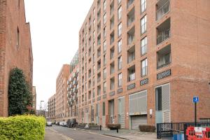 an empty city street with a large brick building at Canning town -2 bed Luxury Apartment in London