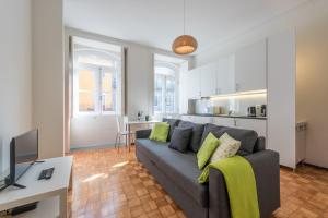 a living room with a gray couch and a kitchen at GuestReady - Virtudes Apartment Balcony 1 in Porto