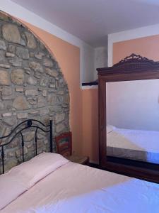 1 dormitorio con pared de piedra, cama y espejo en Casa Manzo, en Montemurro