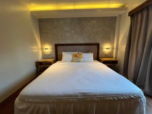- une chambre avec un grand lit blanc et 2 tables de chevet dans l'établissement Vencejos Inn - El Nido, à El Nido