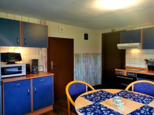 eine Küche mit blauen Schränken und einem Tisch mit einem blauen Tischtuch in der Unterkunft Ferienwohnung Pünter in Surwold