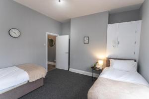 sypialnia z 2 łóżkami i zegarem na ścianie w obiekcie May Disc - Long Stay - Contractors w Bristolu