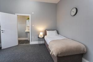 sypialnia z łóżkiem i zegarem na ścianie w obiekcie May Disc - Long Stay - Contractors w Bristolu