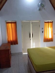 1 dormitorio con 1 cama, cortinas de color naranja y puerta en Putri Nyale Bungalow, en Kuta Lombok