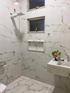 uma casa de banho branca com um lavatório e um chuveiro em Paraíso Panorâmico Beira do Lago em Caldas Novas